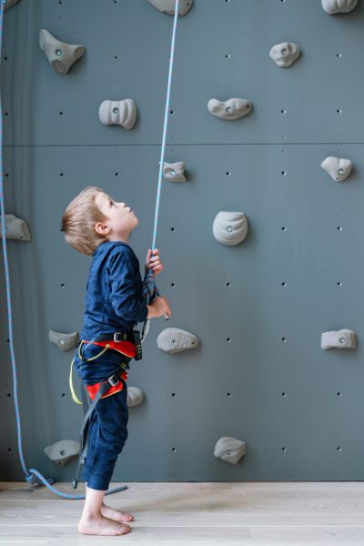 a-brave-little-climber-boy-prepares-to-climb-a-cli-2022-03-02-22-18-10-utc